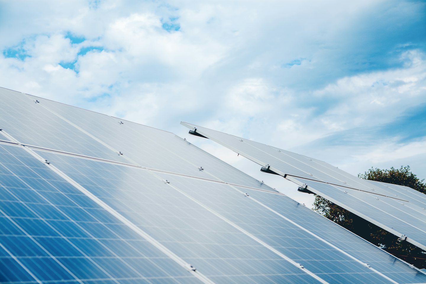 Multiple solar panels angled towards a clear blue sky.